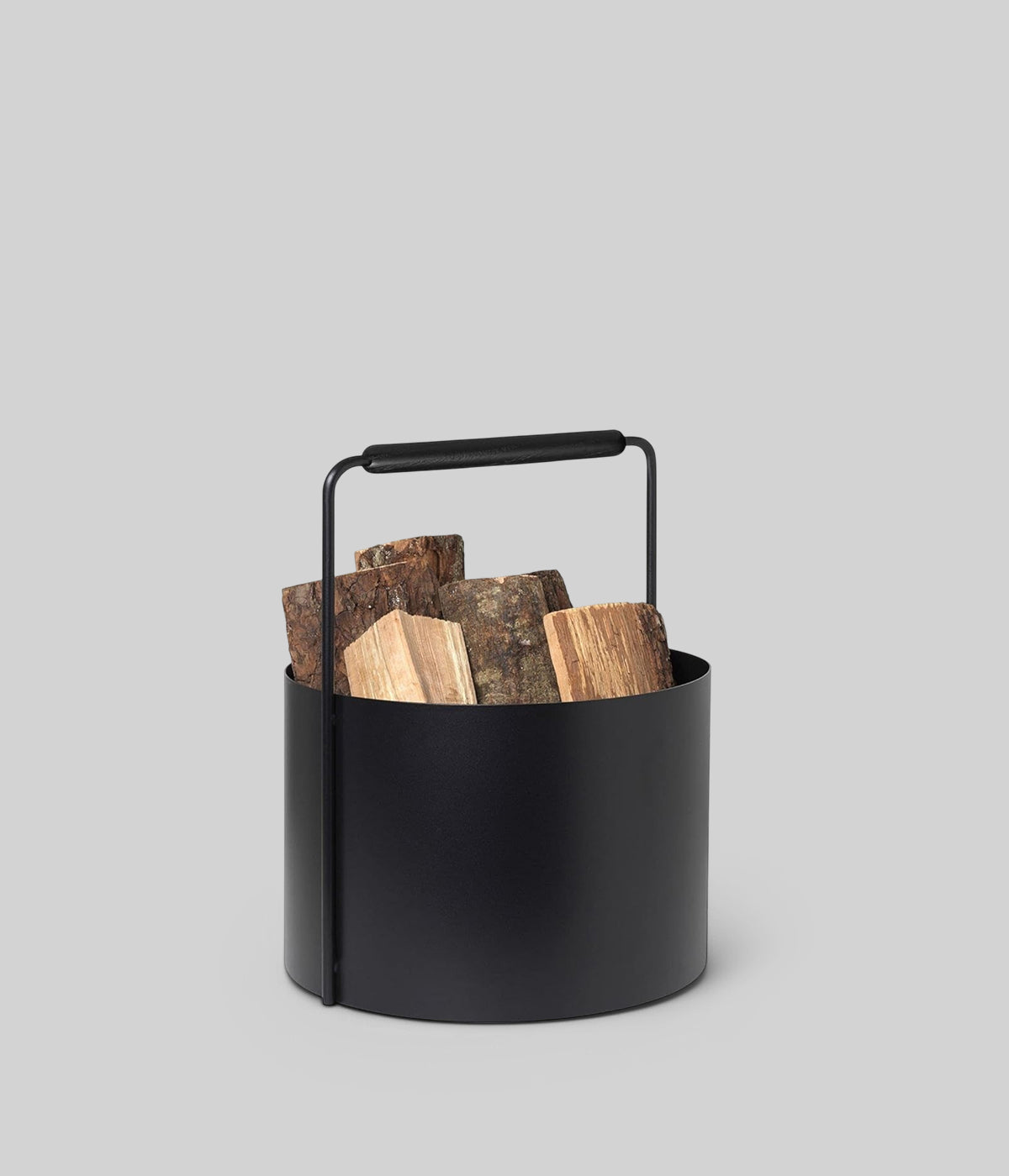 Indoor log holder with oak handle and black steel body for modern hearths