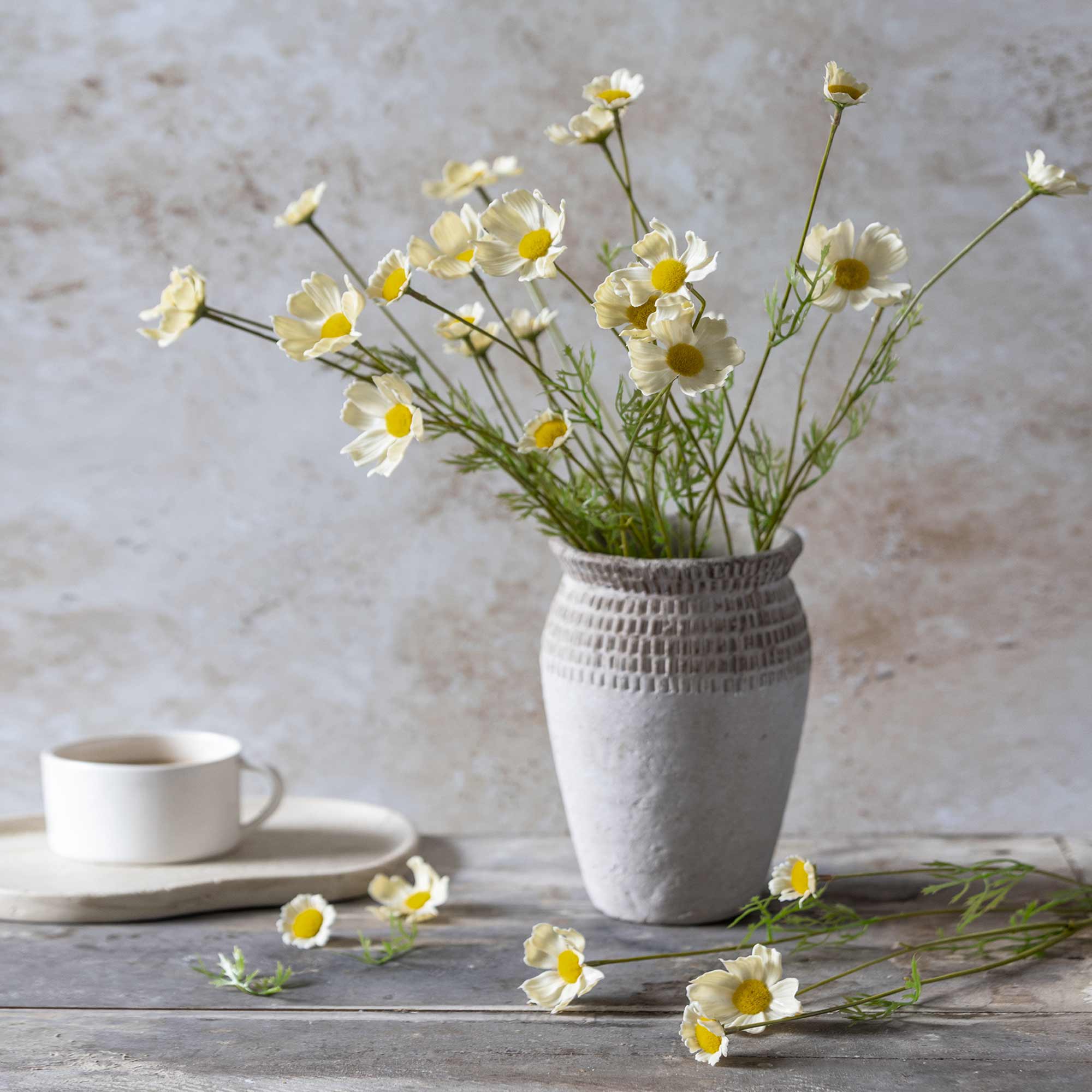 Artificial cosmos arranged loosely in a ceramic vase for a meadow-style display
