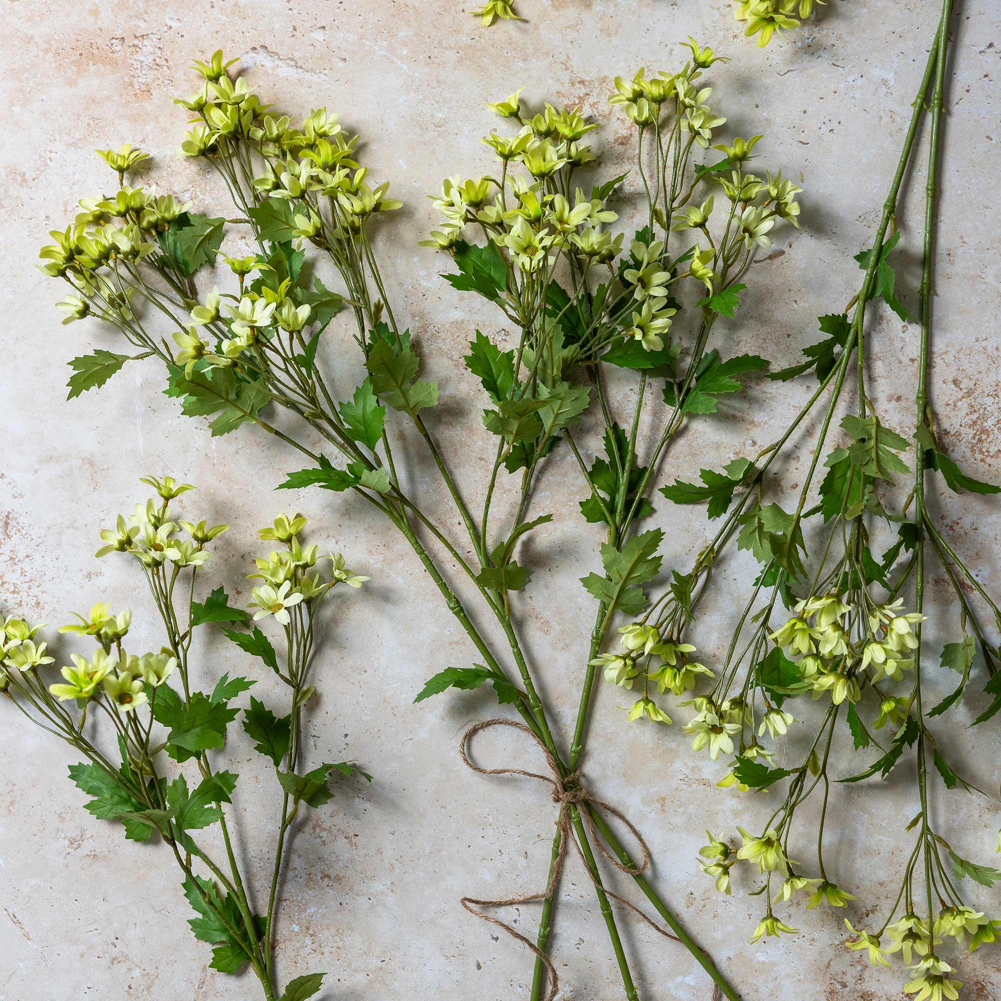 Cream-toned artificial daisy flowers with layered blooms and green foliage