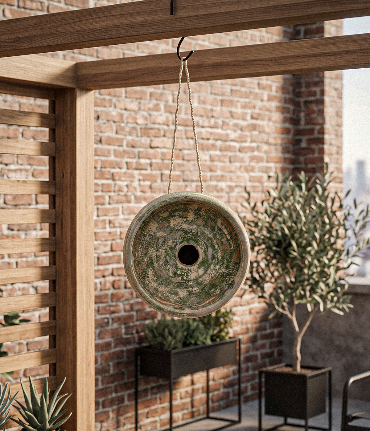 Garden Sage terracotta birdhouse hanging by jute rope from a wooden pergola in a planted outdoor setting