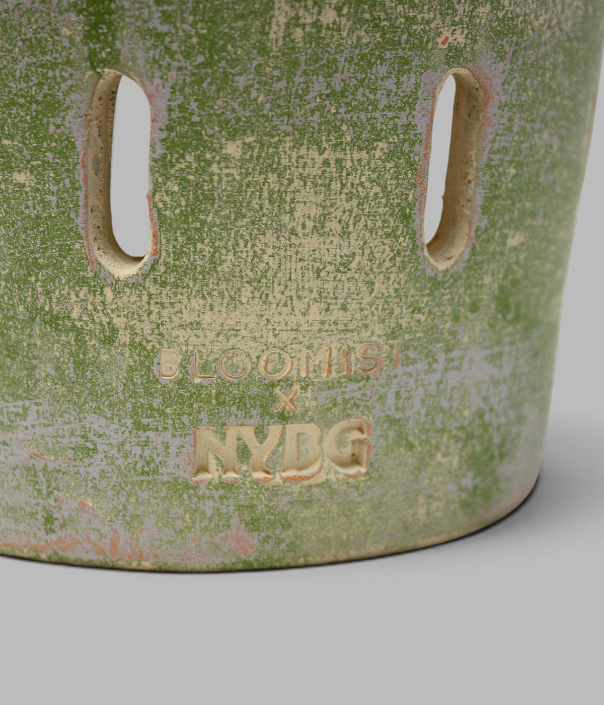 Close-up of the Garden Sage terracotta orchid pot showing vertical ventilation openings and impressed Bloomist x NYBG branding