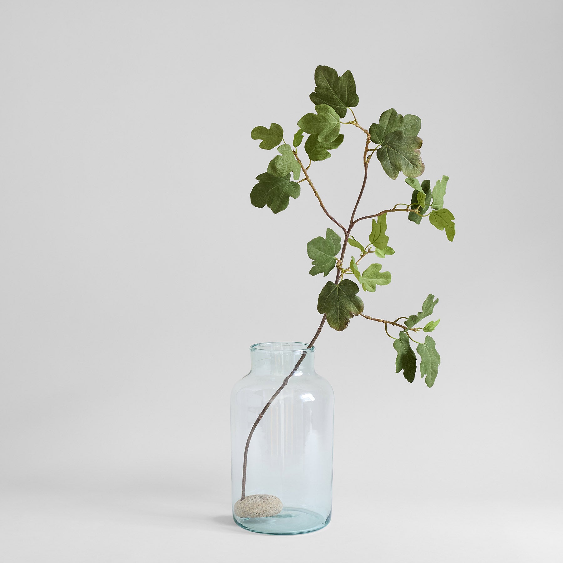 River-worn stone flower frog supporting a leafy stem in a clear bottle