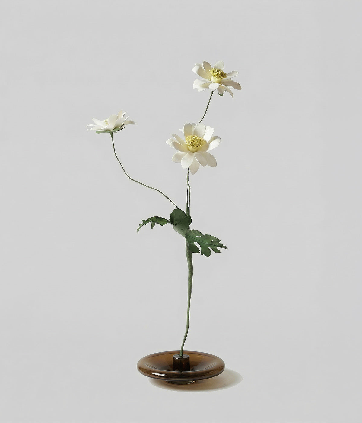 Wax-coated paper chrysanthemum flower in a small glass base
