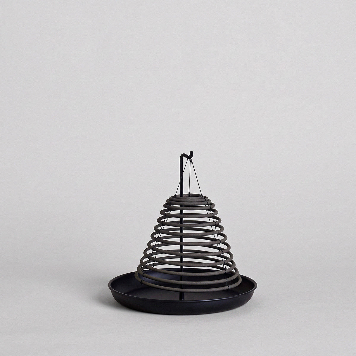 Black citronella incense coil displayed on black metal stand with round base