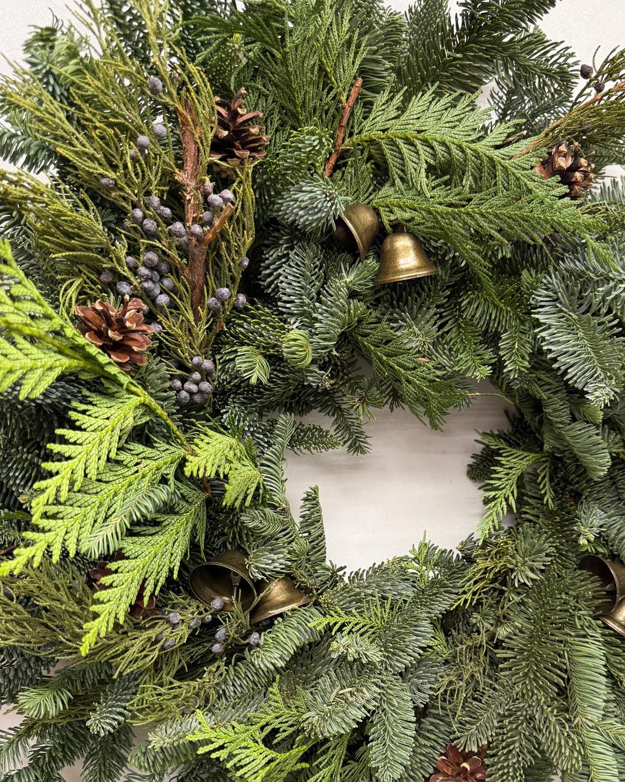 Close-up of Clara juniper wreath with antique-style bells, blue berries, pine cones, fir, and cedar
