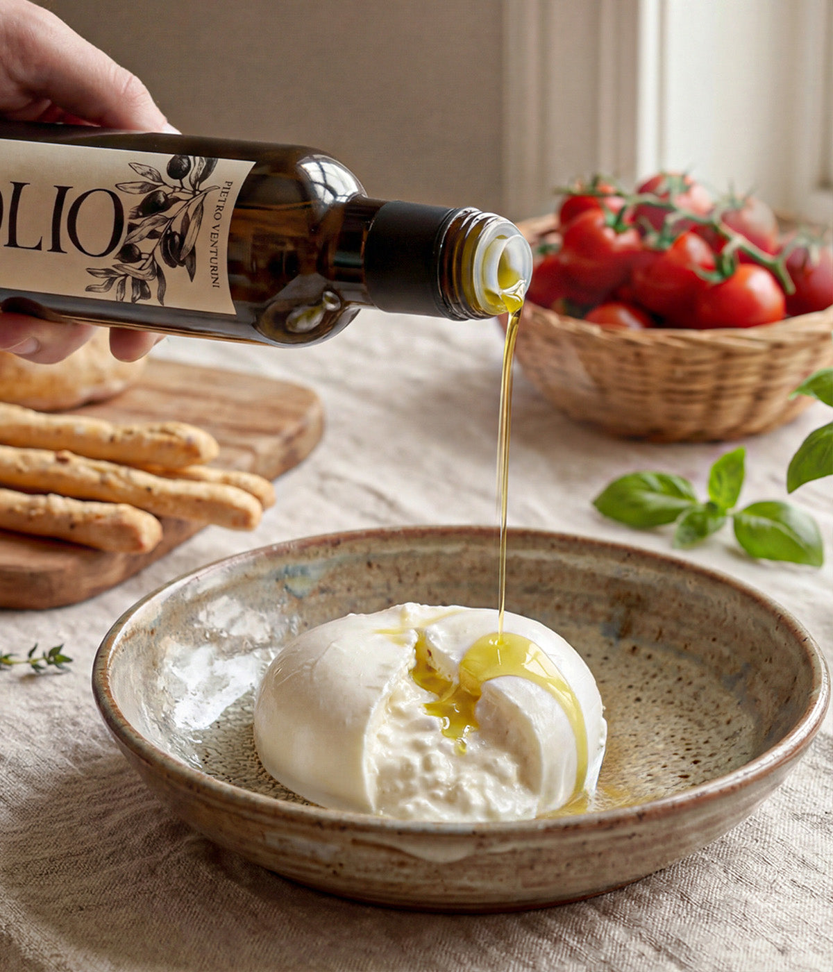 Extra virgin olive oil being poured over fresh burrata cheese with tomatoes and bread