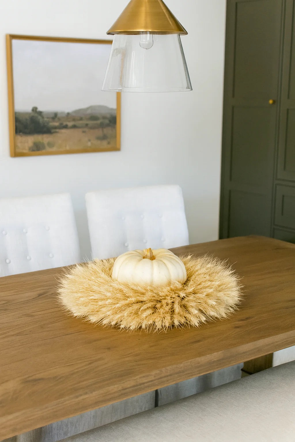 Blonde wheat wreath laid flat as centerpiece with white pumpkin in center