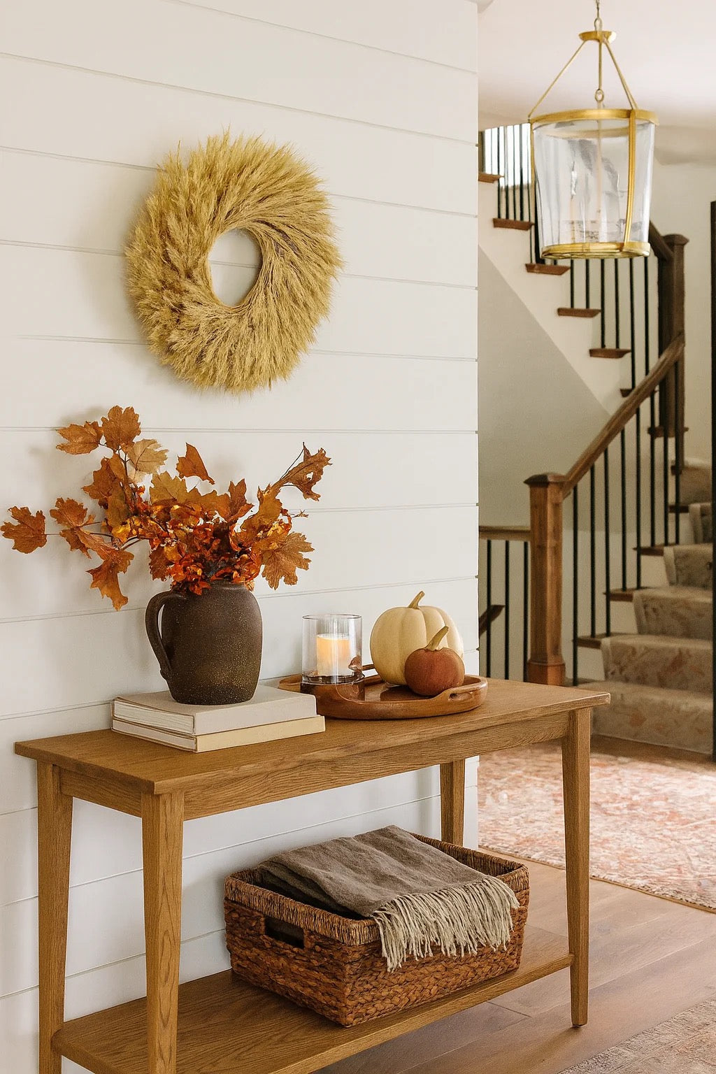 Wheat harvest wreath on wall above wooden console with fall decor and books