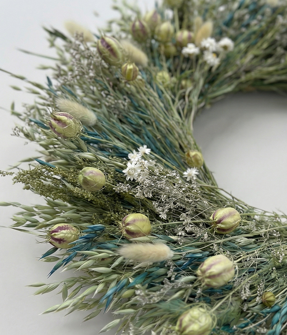 Close-up of Celeste wreath showing teal-blue dyed oats, bunny tails, and ammobium daisies