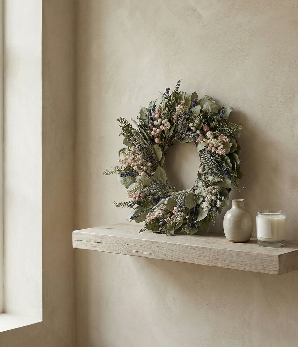 Everyday wreath decor styled on a floating wood shelf with ceramic vessels