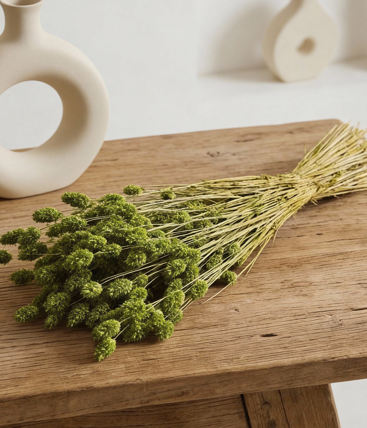 Dried harding grass displayed on rustic wood table with neutral ceramic decor