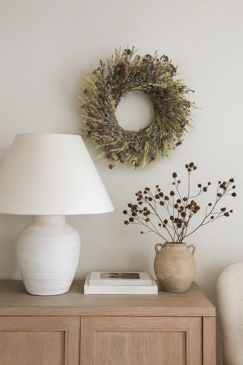 Dried herb wreath displayed on neutral wall above wooden console