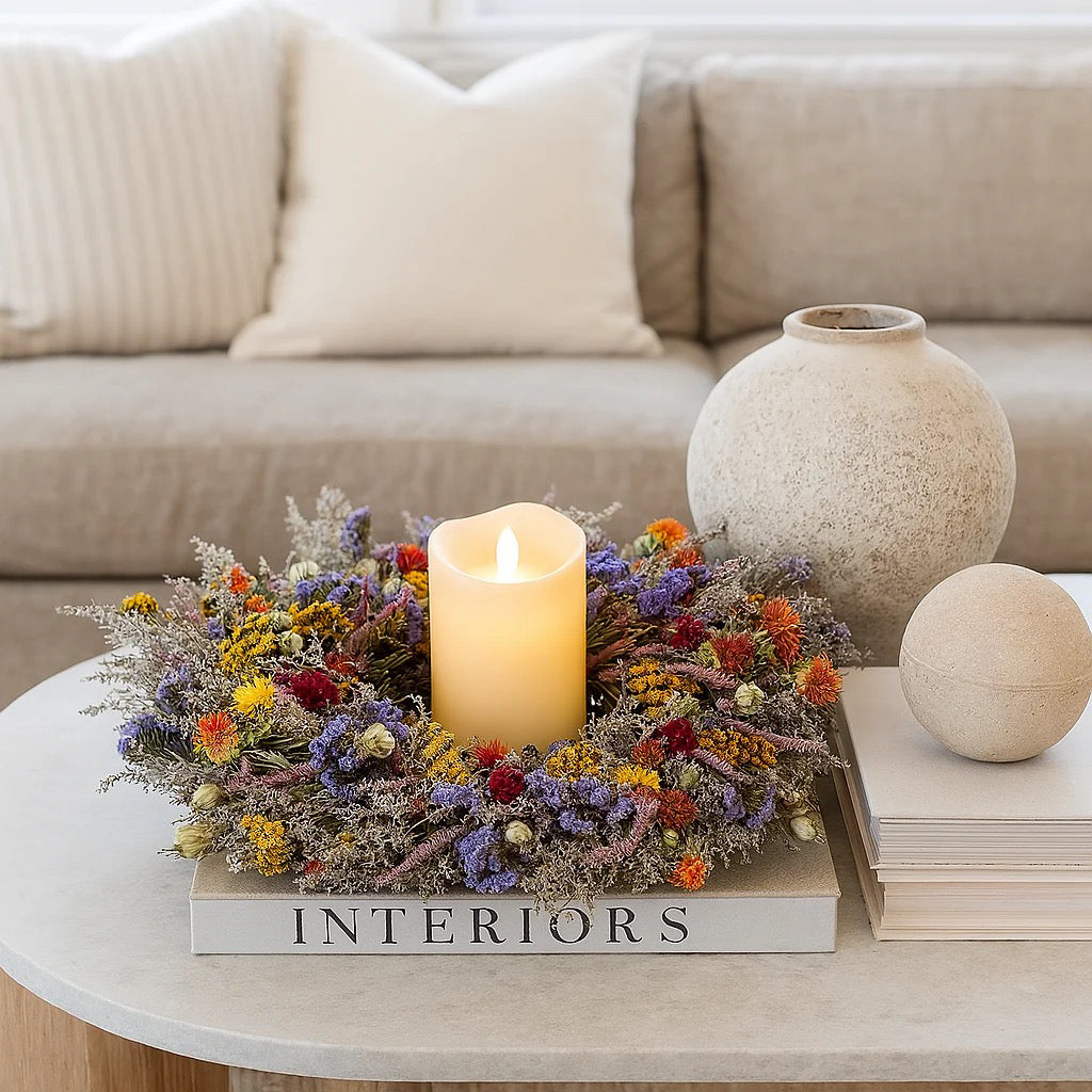 Dried spring flower wreath displayed flat as table centerpiece with lit candle in center