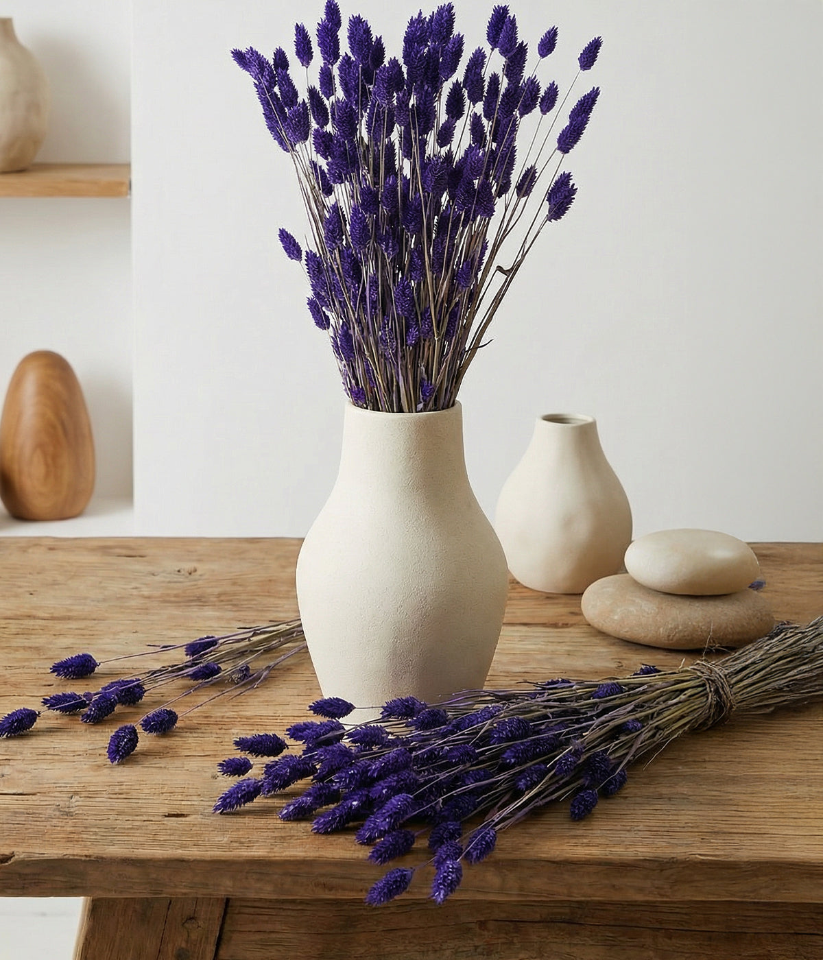Purple phalaris displayed in white ceramic vase on rustic wood table with neutral decor