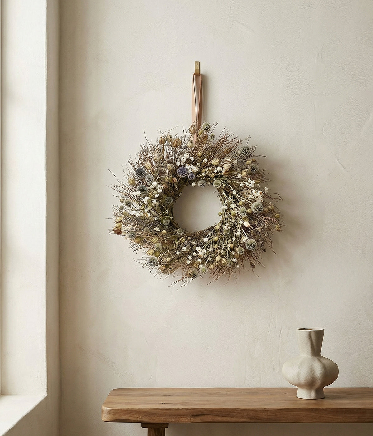 Rosalind Thistle and Daisy Wreath hanging indoors above a wooden console with ceramic accents