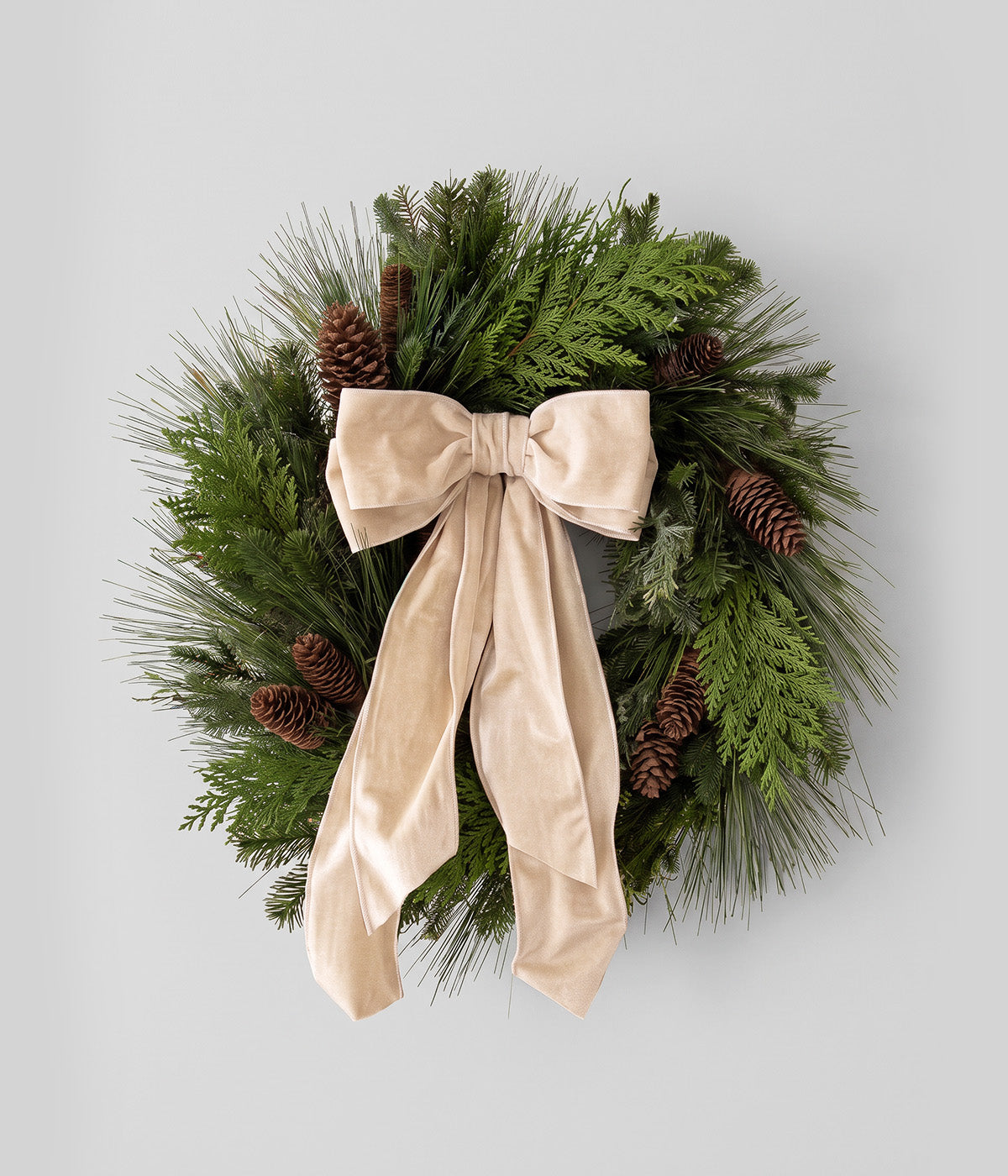 Eleanor fresh pine wreath with ivory velvet bow, mixed evergreen foliage, and natural spruce pine cones