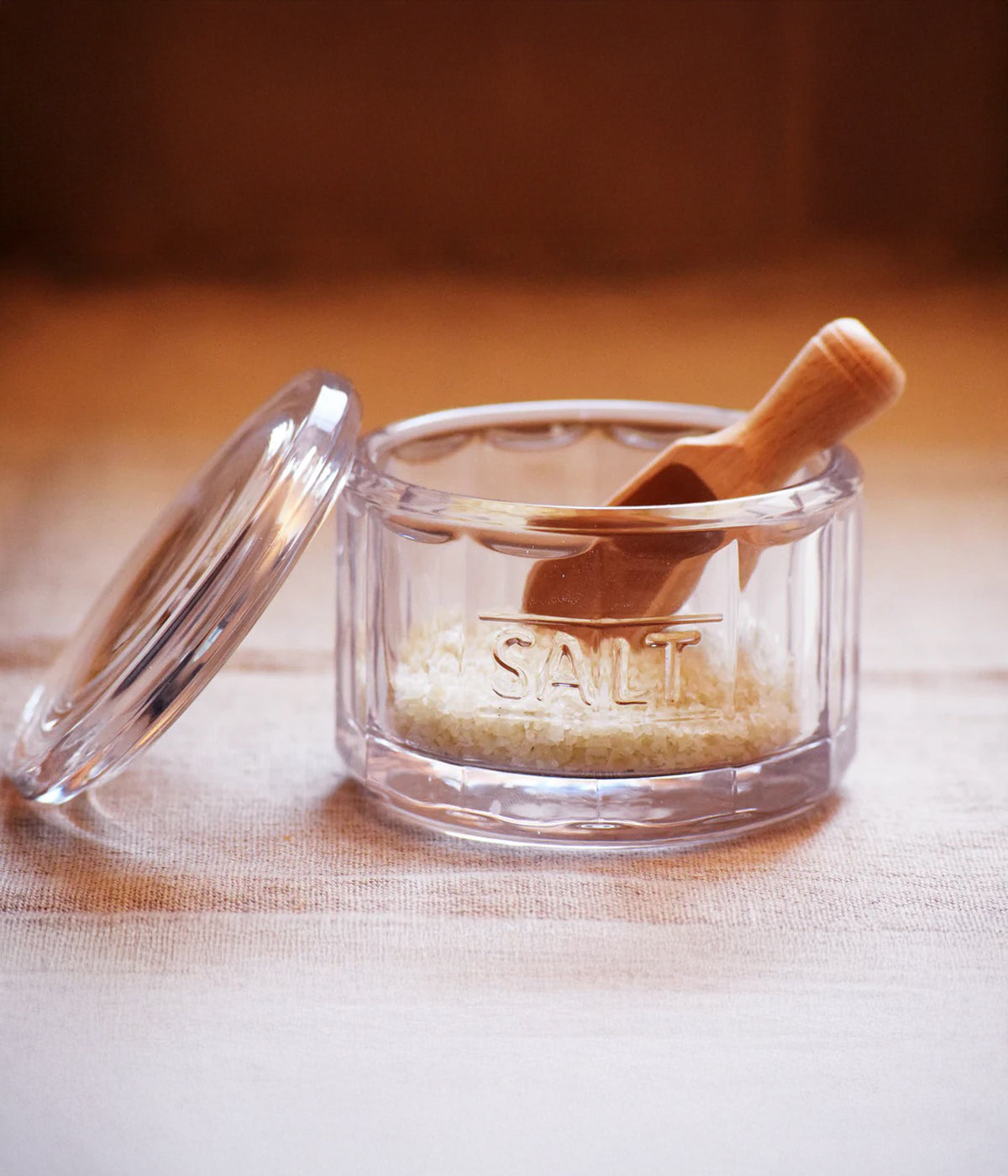 Sculpted glass salt cellar for countertop storage with matching wood scoop inside