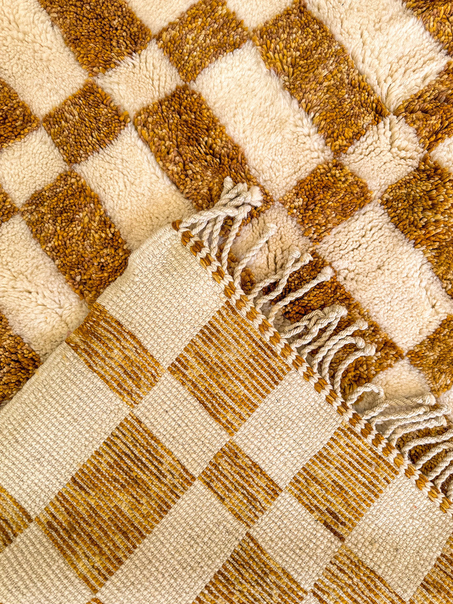 Artisan-made Moroccan rug with gold checkered design and plush feel for grounding interiors