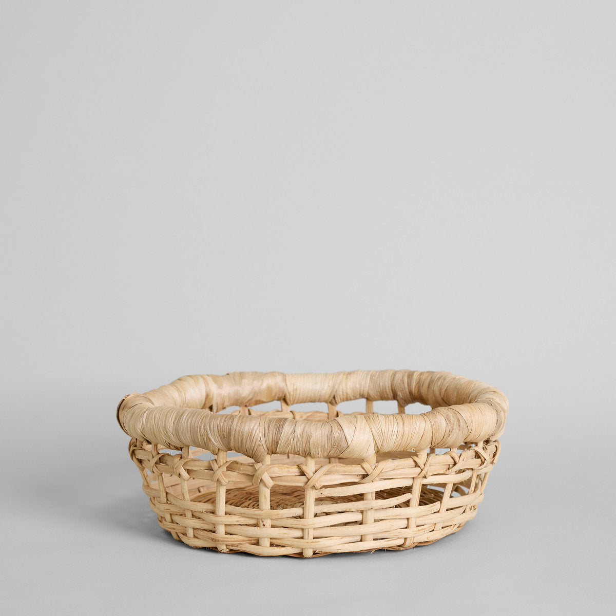 Shallow woven basket with fabric lining displayed on a white surface