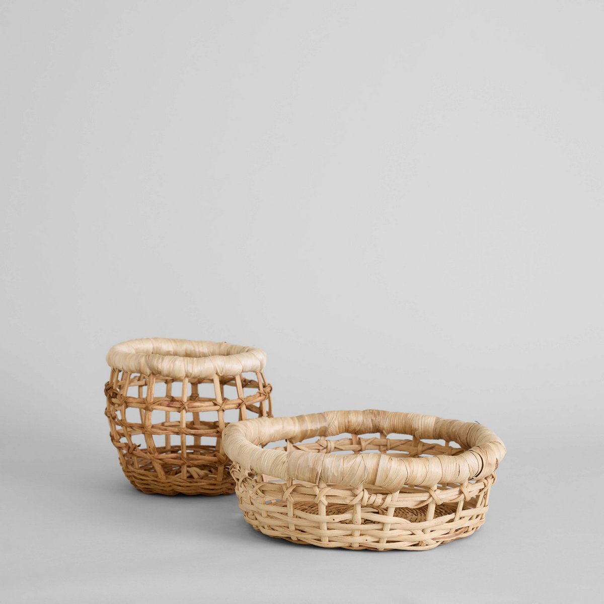 Set of two woven baskets with fabric lining on a neutral background