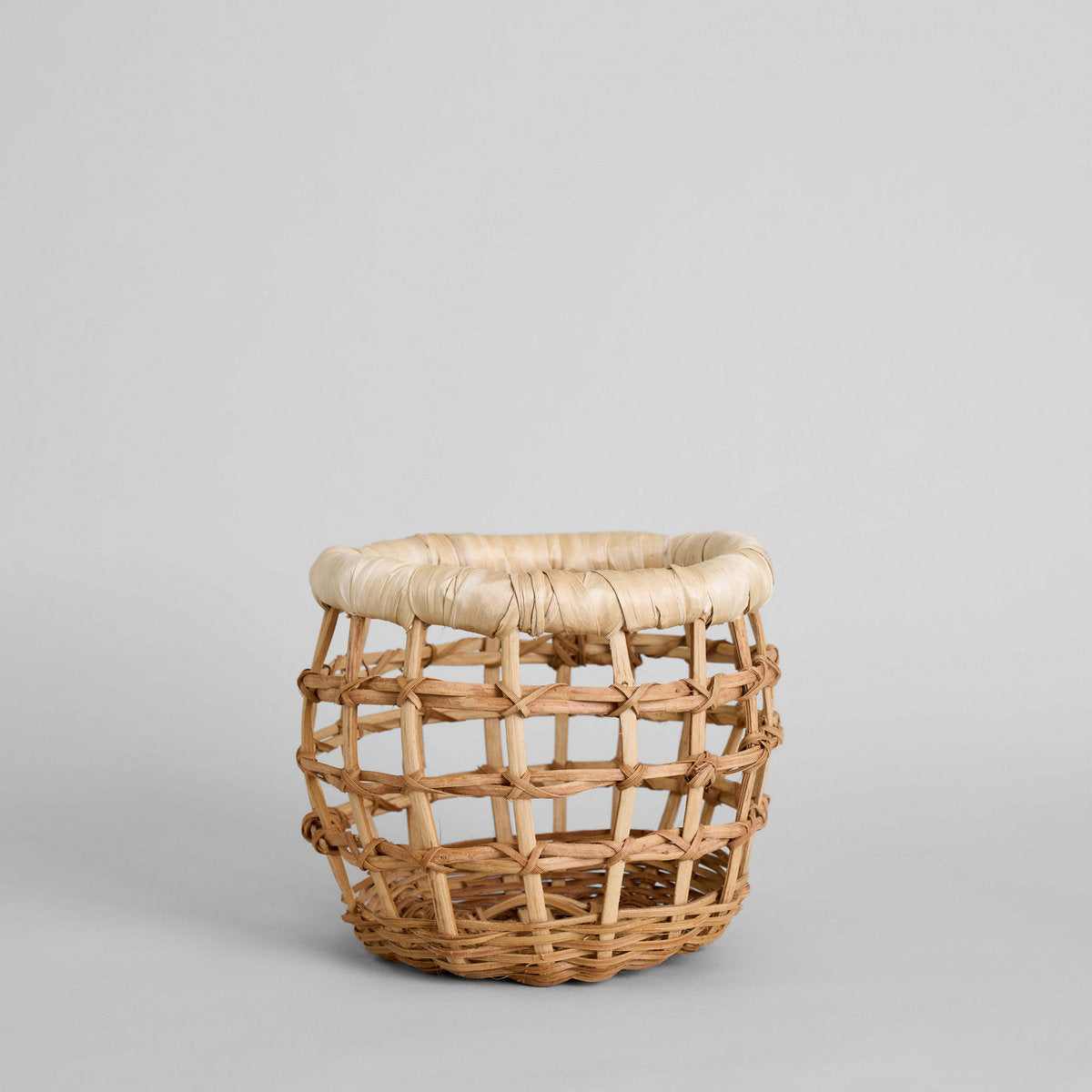 Side view of small round woven basket with open weave design