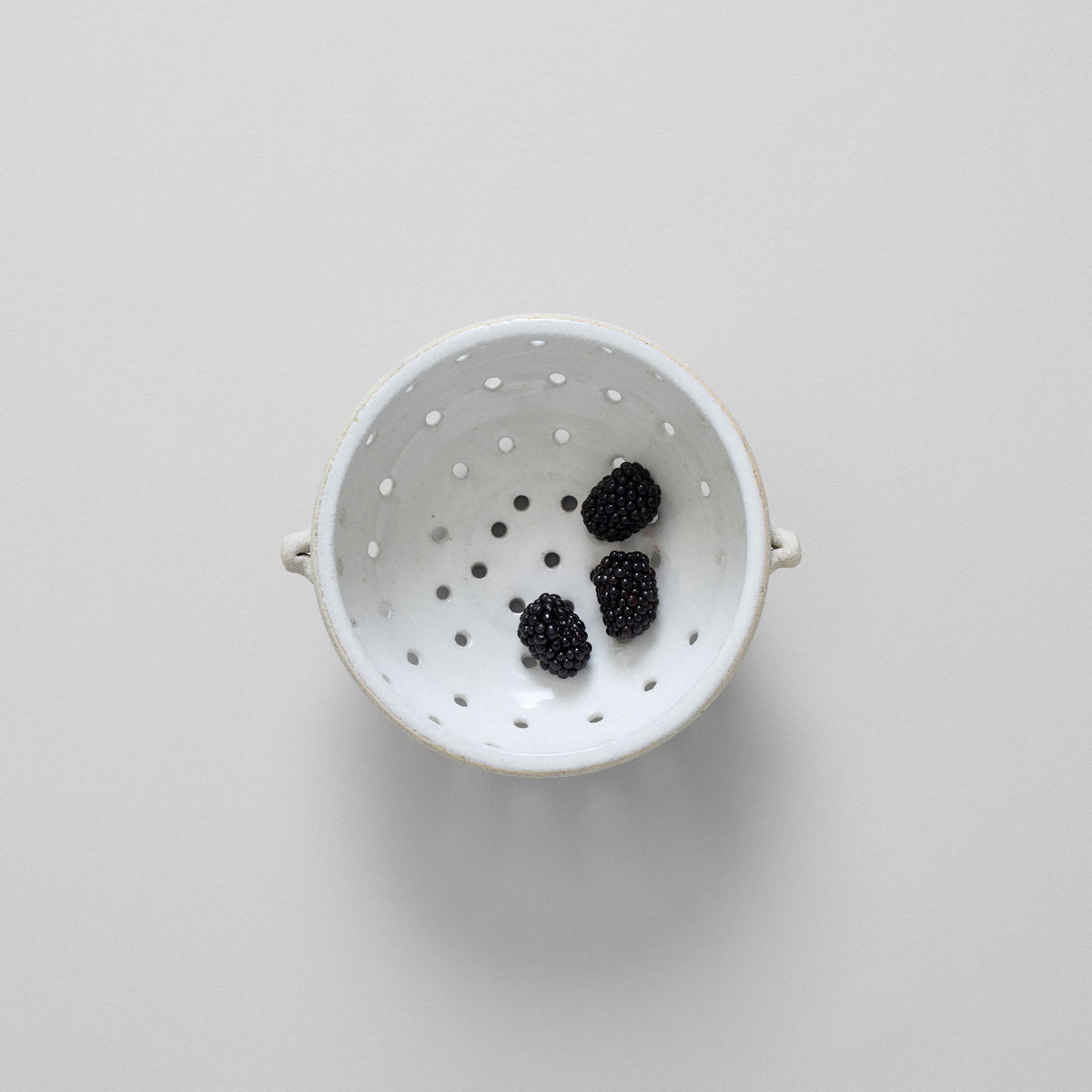 White ceramic fruit colander with drainage holes for rinsing berries and produce