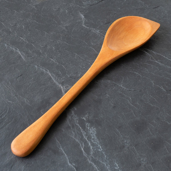 Cherry wood spoon on a dark gray stone surface