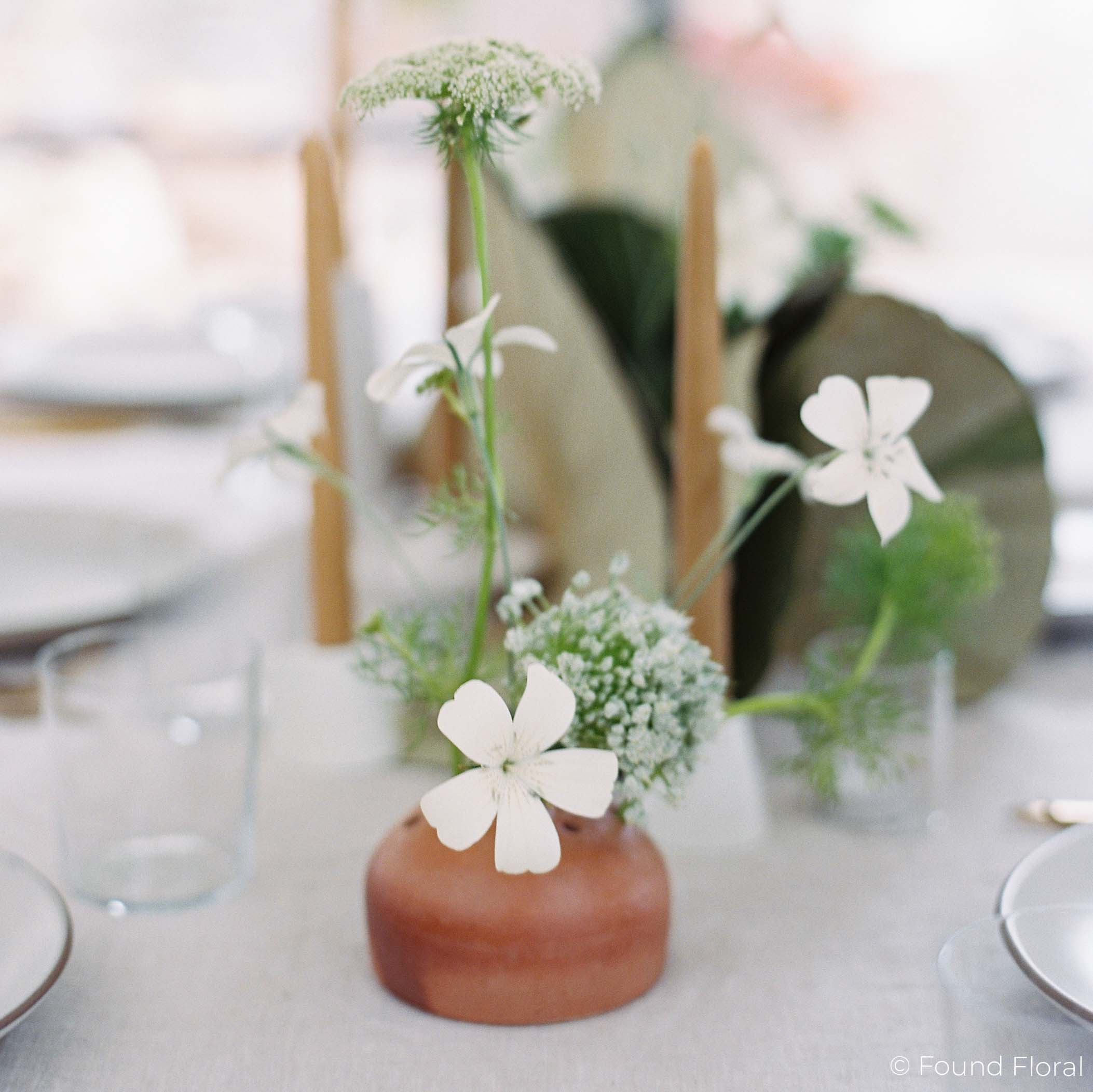 Small frog vase with white blooms on formal table setting