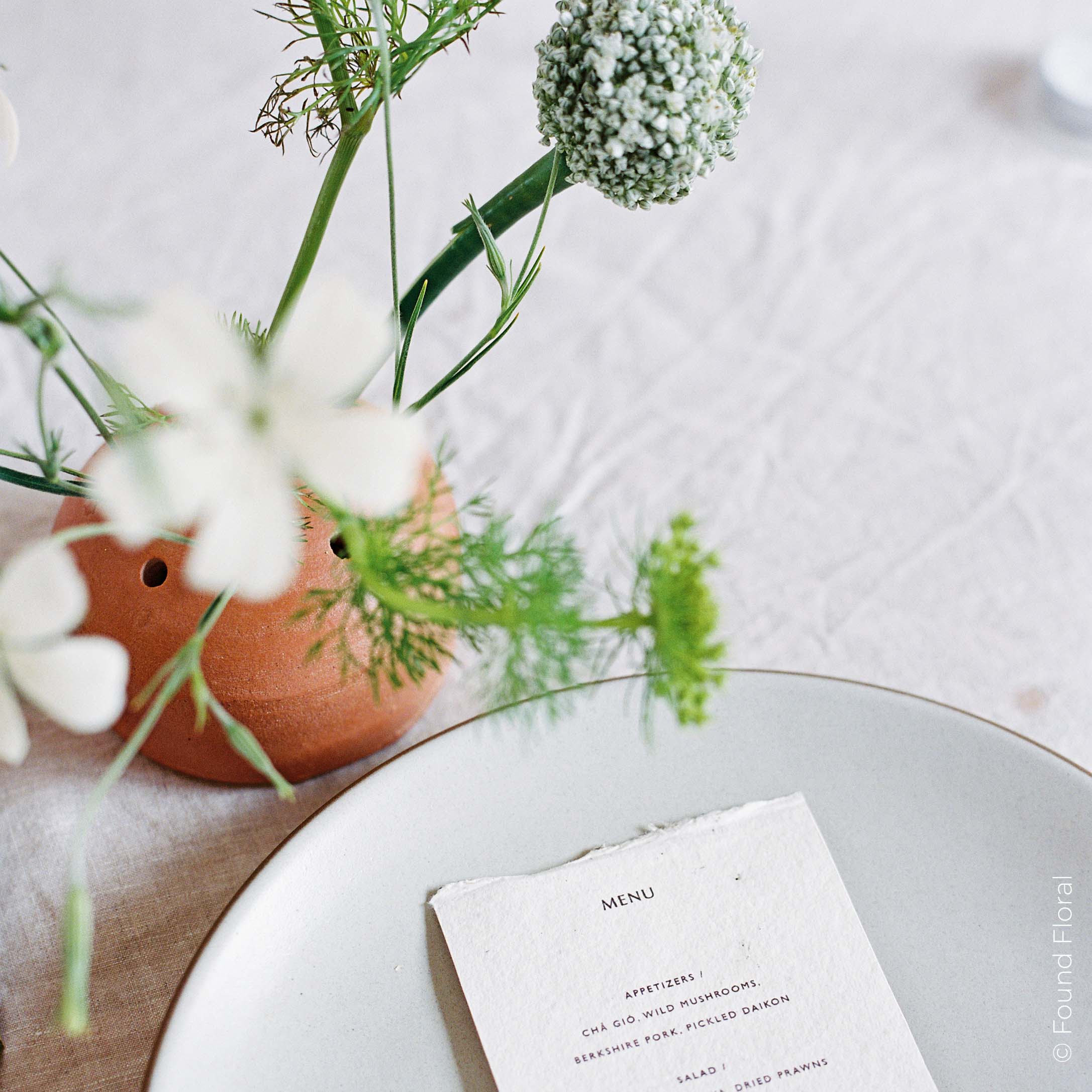 Frog vase with fresh stems on a formal table setting