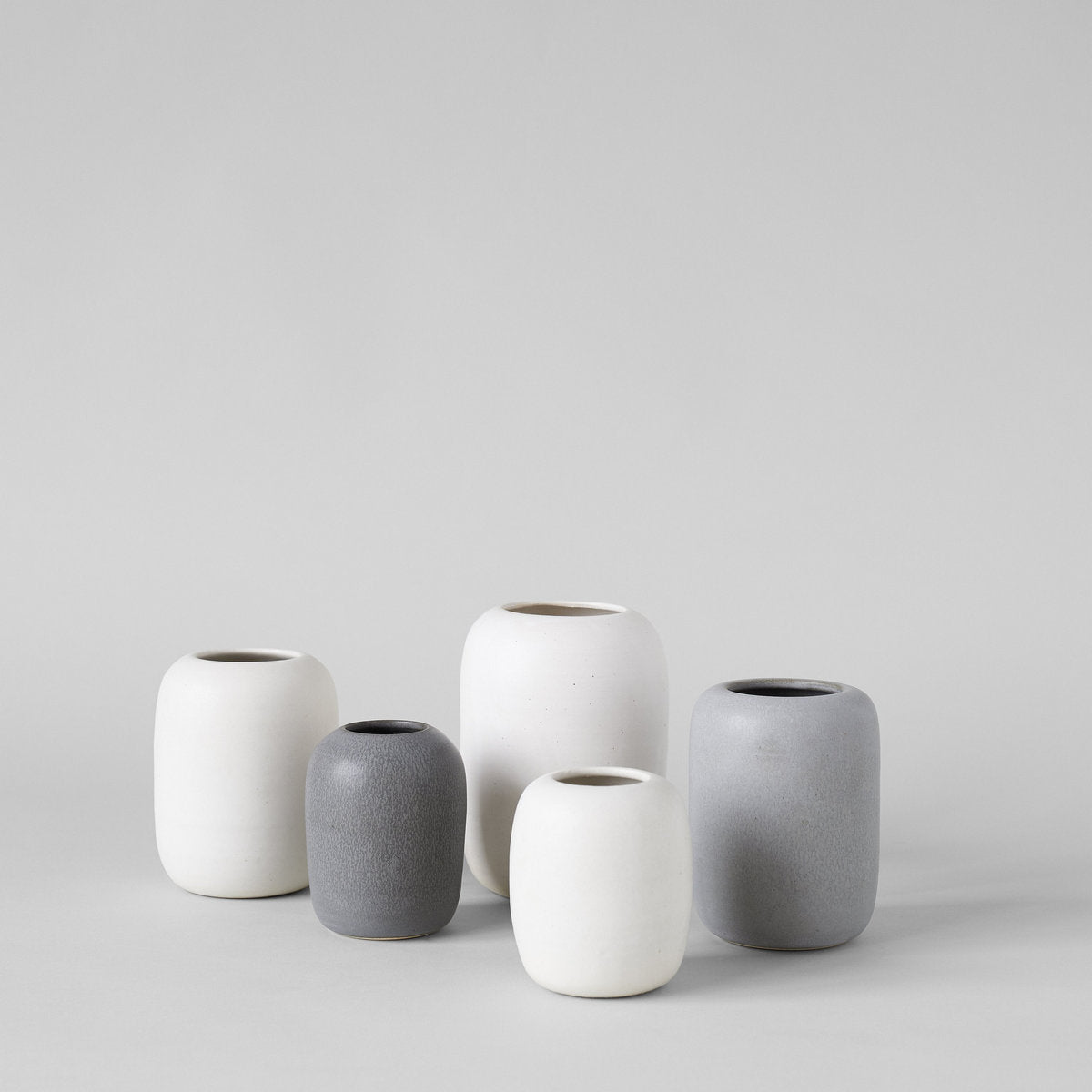 Group of grey ceramic vases arranged with white and charcoal tones