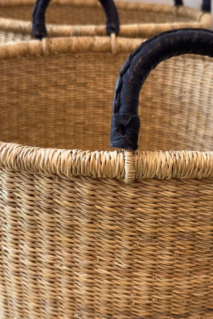 Low woven basket with sturdy base and black handles