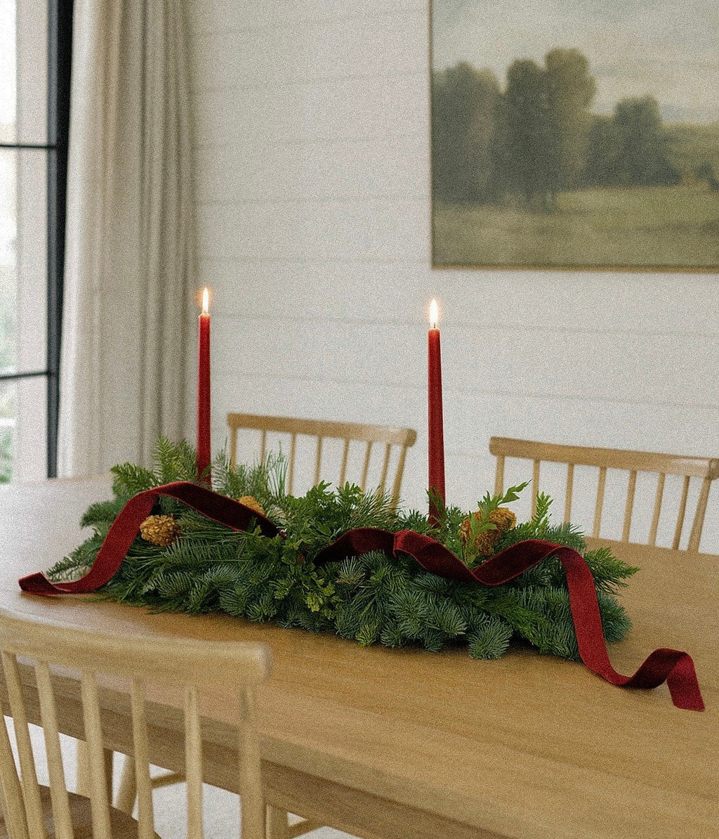 Vivienne mantel garland arranged on a dining table with burgundy velvet and two red taper candles
