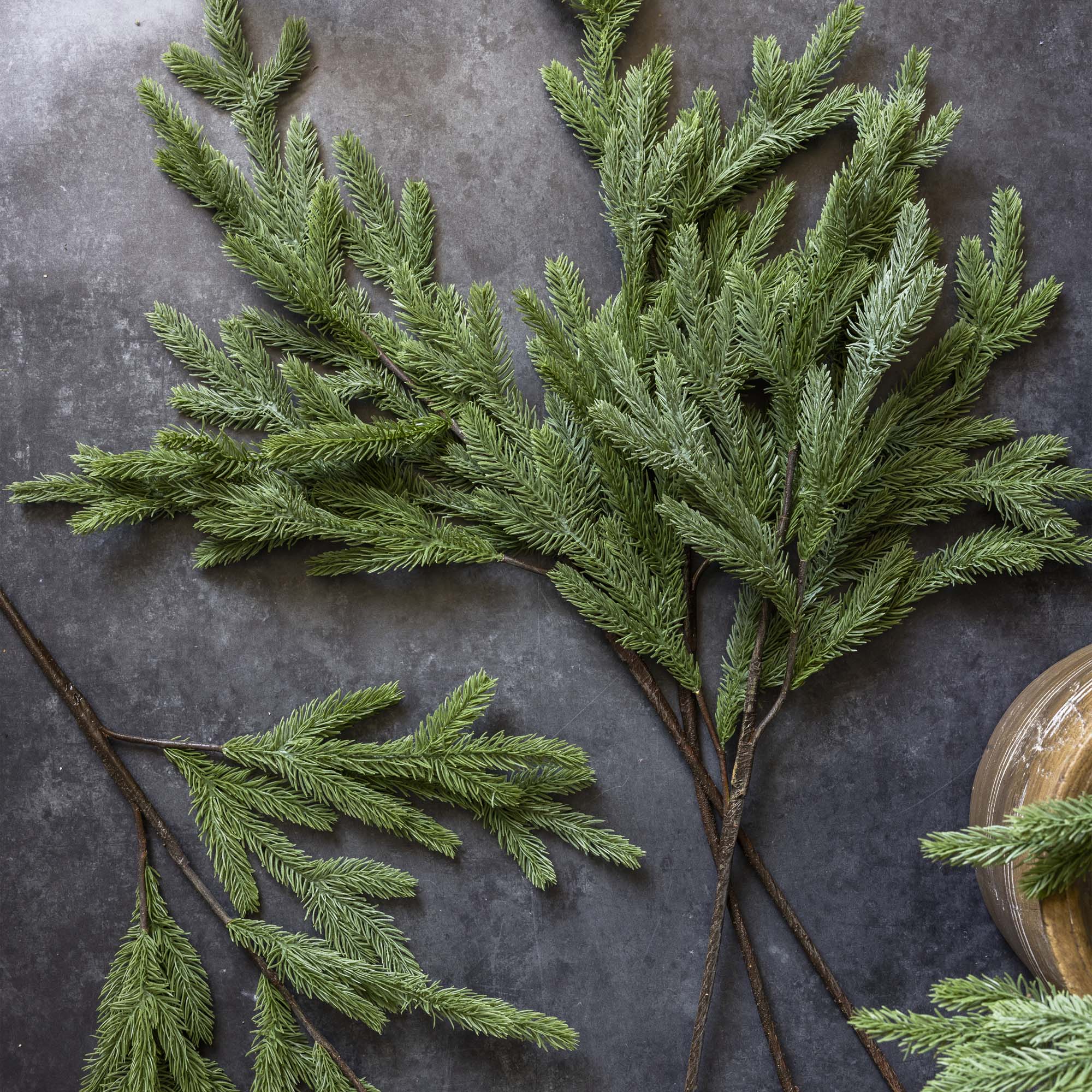 Artificial foxtail pine stem with layered green spines arranged in a winter centerpiece