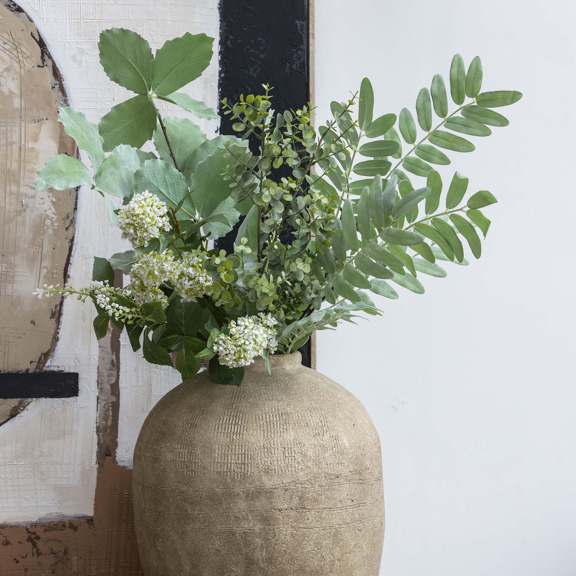 Faux foliage bunch displayed in a statement vase on console with natural greenery tones