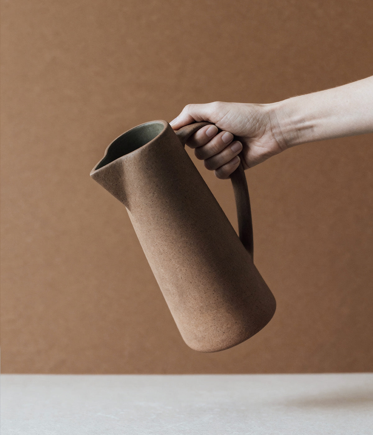 clay pitcher with glazed interior and sculptural unglazed exterior