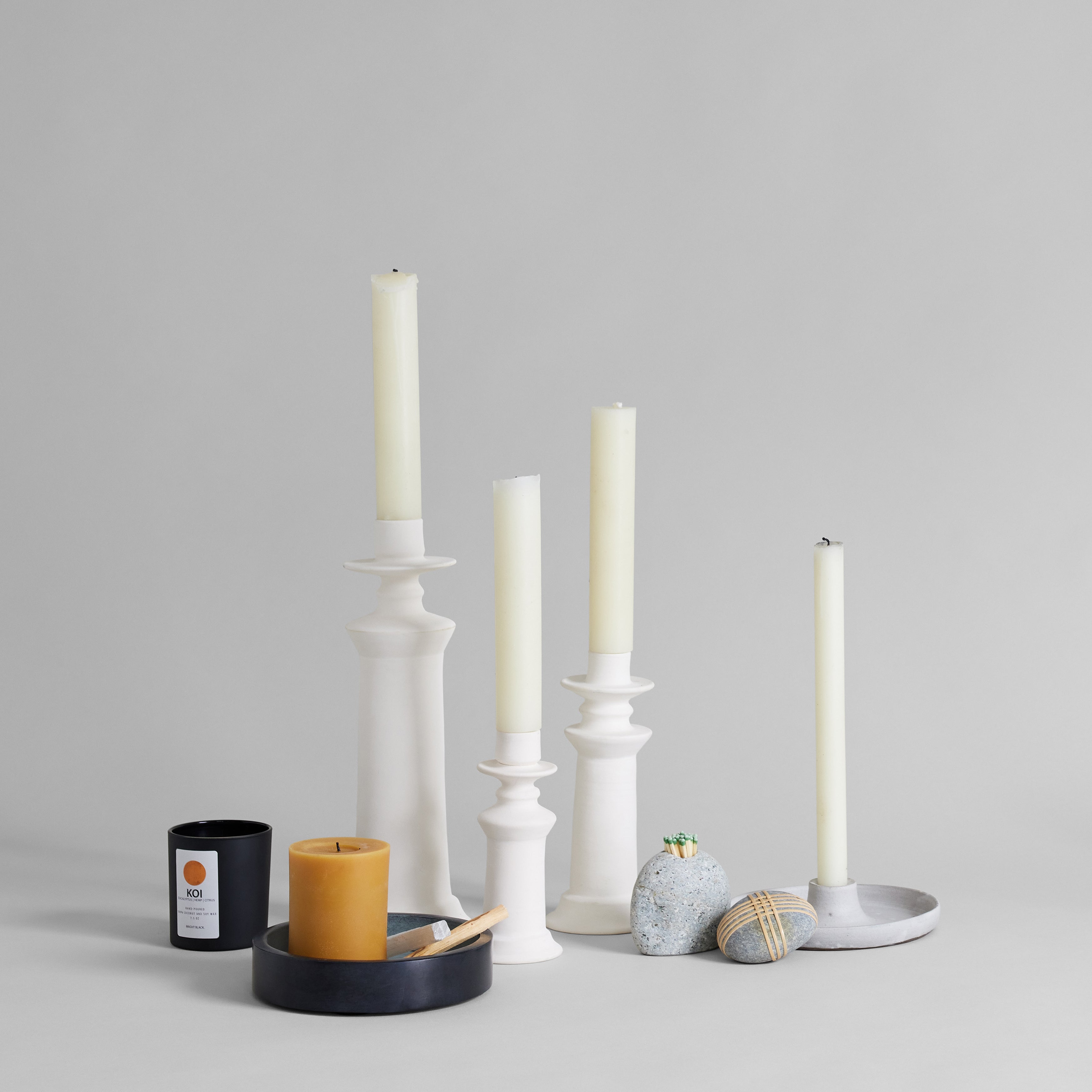 Unglazed white ceramic candlestick arranged with home decor objects